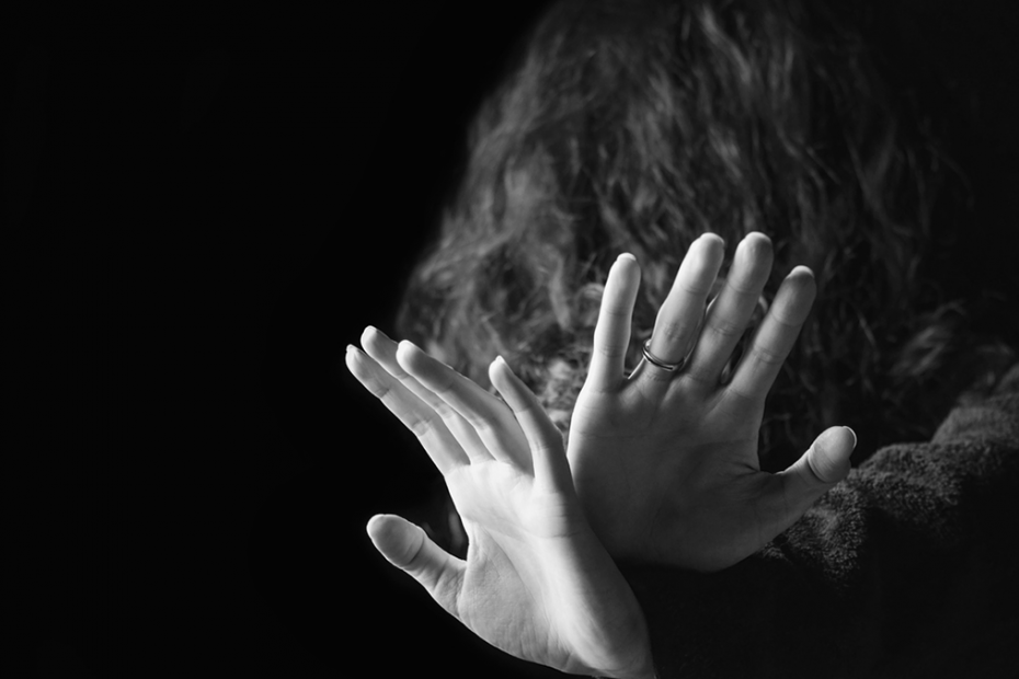 Black and White photo of a woman with her hands raised, protecting her face