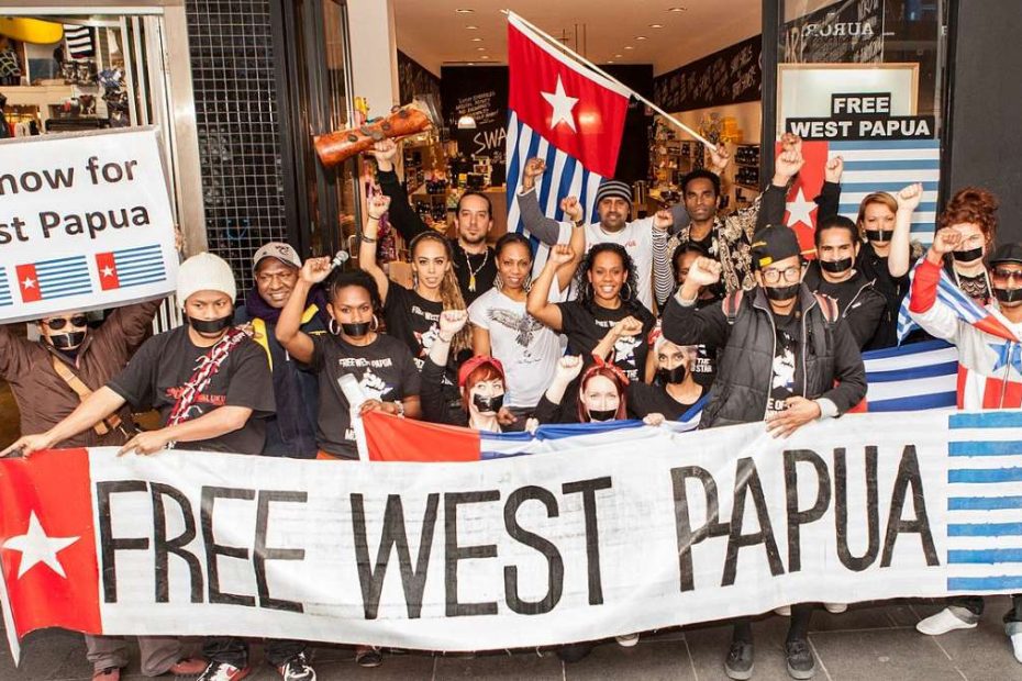People being a banner saying "Free West Papua" with the West Papua flag