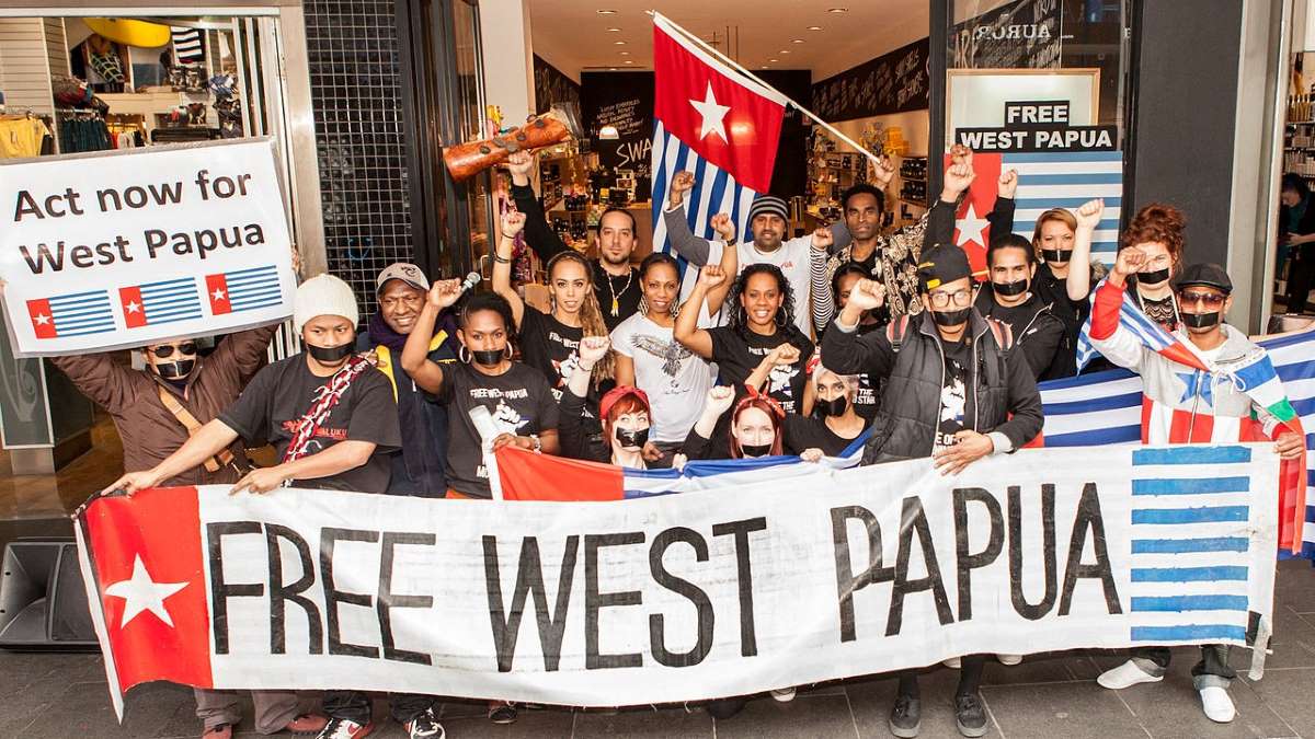 People being a banner saying "Free West Papua" with the West Papua flag