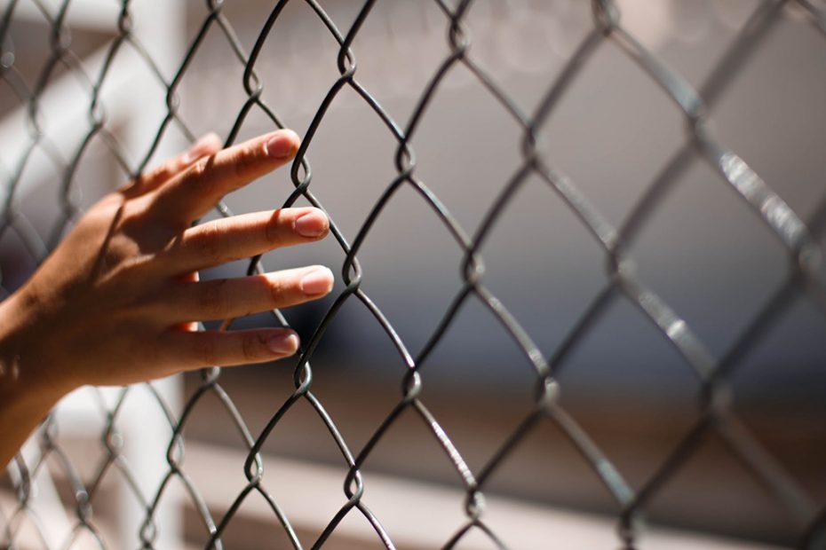 Hand reaching through wire fence