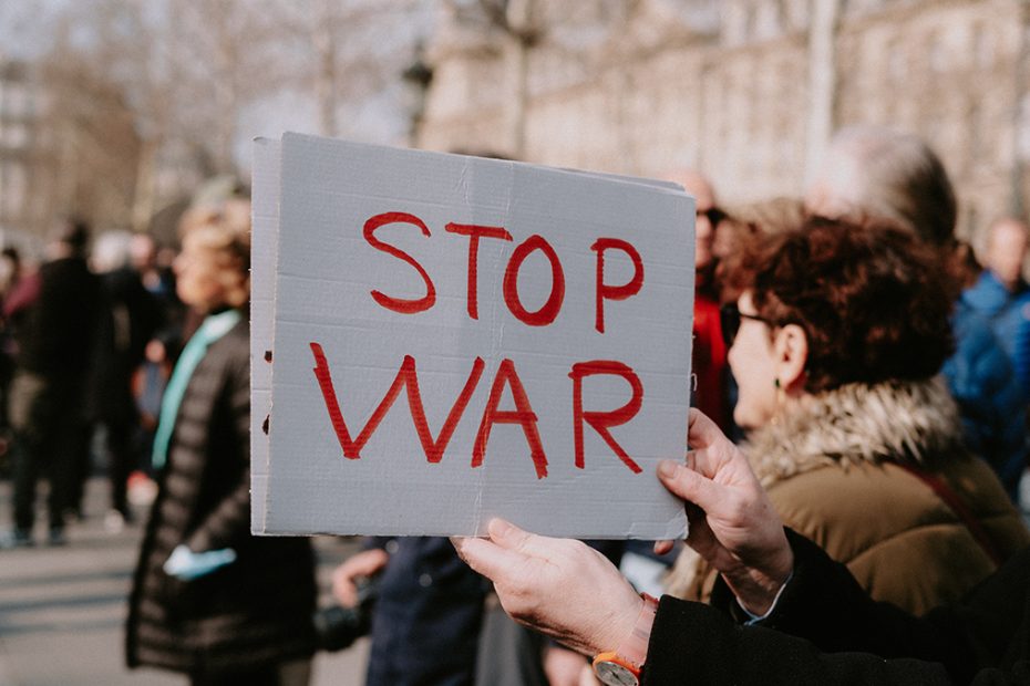 A "Stop War" sign is in the centre of the frame as part of a protest on a European city street.