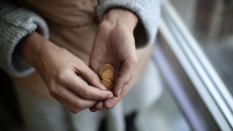 A womans hands, holding a meagre amount of coins